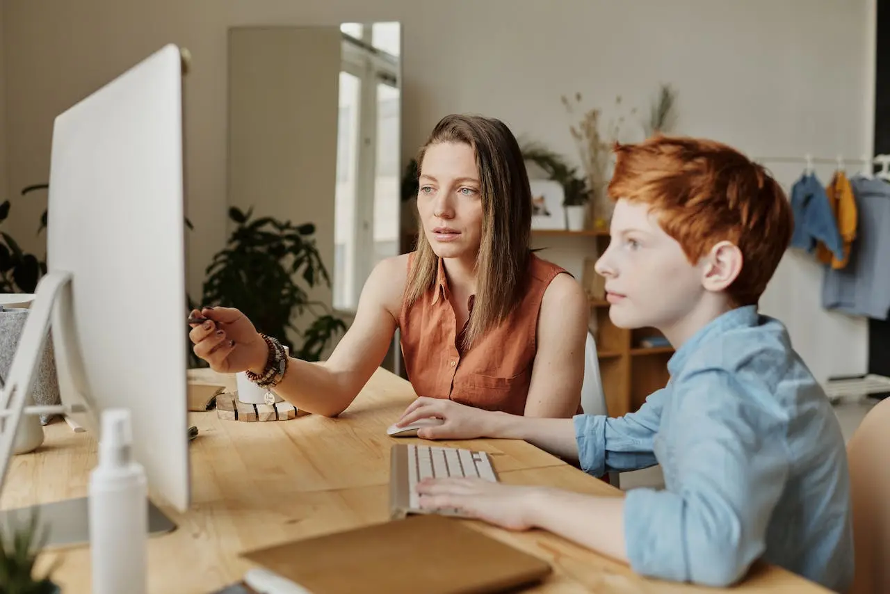 Mother teaching her son in a computer